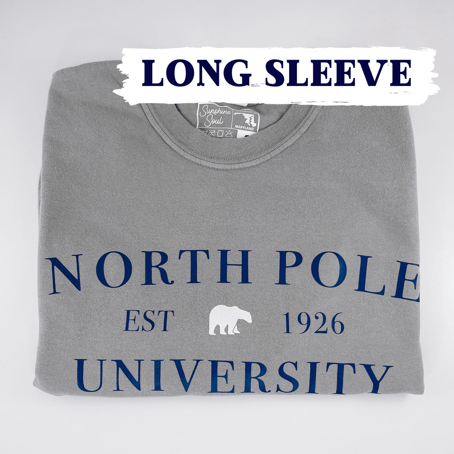 North Pole University long sleeve graphic tee by SunshineSoulMD featuring festive holiday-themed design on soft fabric.